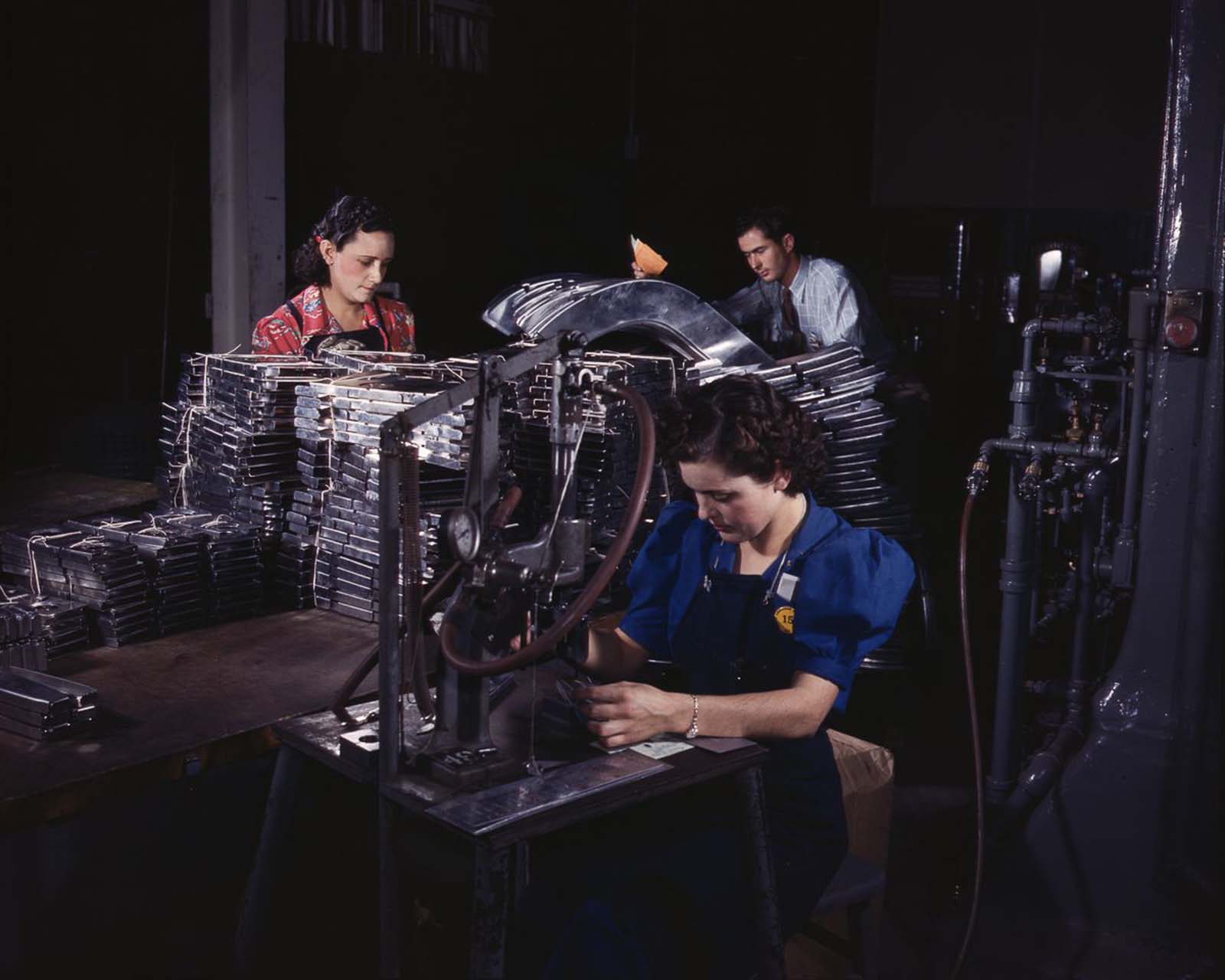 #11 Workers feed sections of sheet metal through a pneumatic numbering machine at the North American Aviation plant in Inglewood, California, 1942.