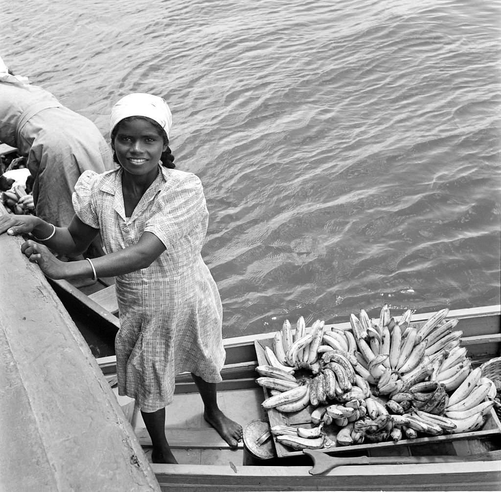 #123 A local women loads bananas onto a boat in the harbor in Bridgetown, 1946
