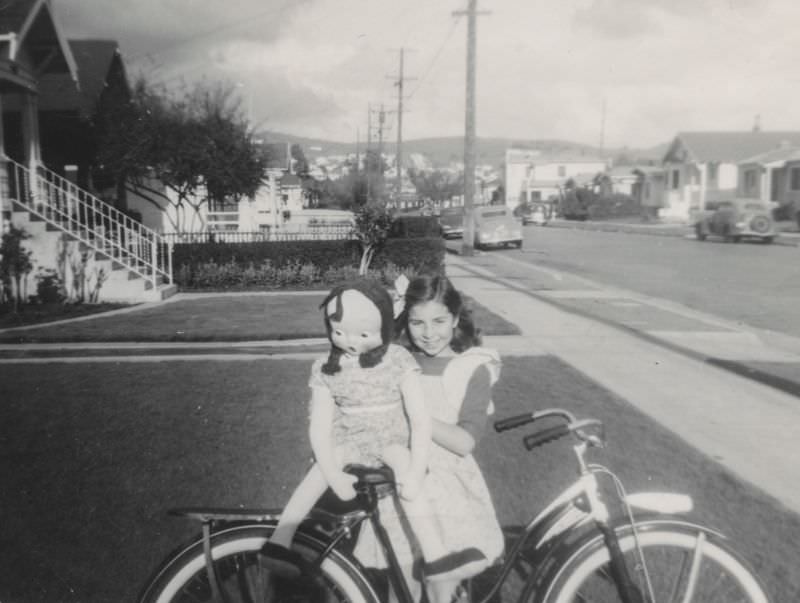 #17 Little girl poses with her doll and bicycle, 1940s