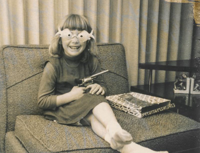 #25 Little girl carrying a toy gun and wearing goofy glasses, December 1964
