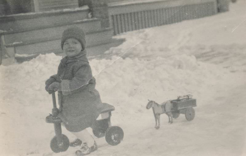 #28 Child playing in the snow on a tricycle