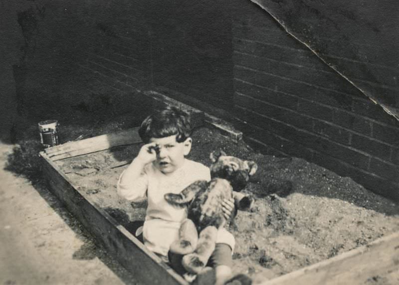 #32 Crying boy with his teddy bear in a sandbox