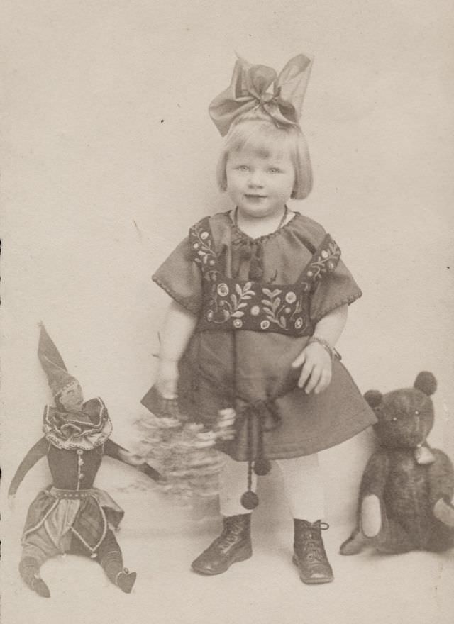 #7 Little girl poses with her teddy bear and stuffed joker, 1920s