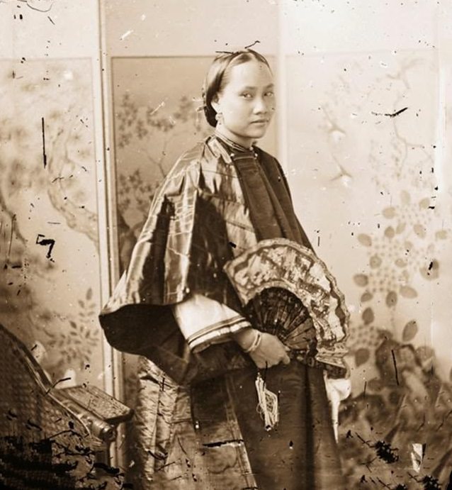 #21 A Cantonese beauty holds an open painted fan and stands before a folding screen Guangdong, 1869