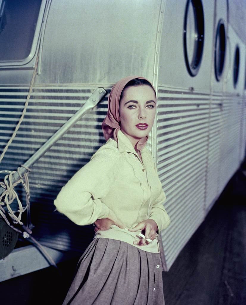 #2 Elizabeth Taylor leaning against a dressing room trailer while smoking a cigarette on the set of 1956 film, ‘Giant’.