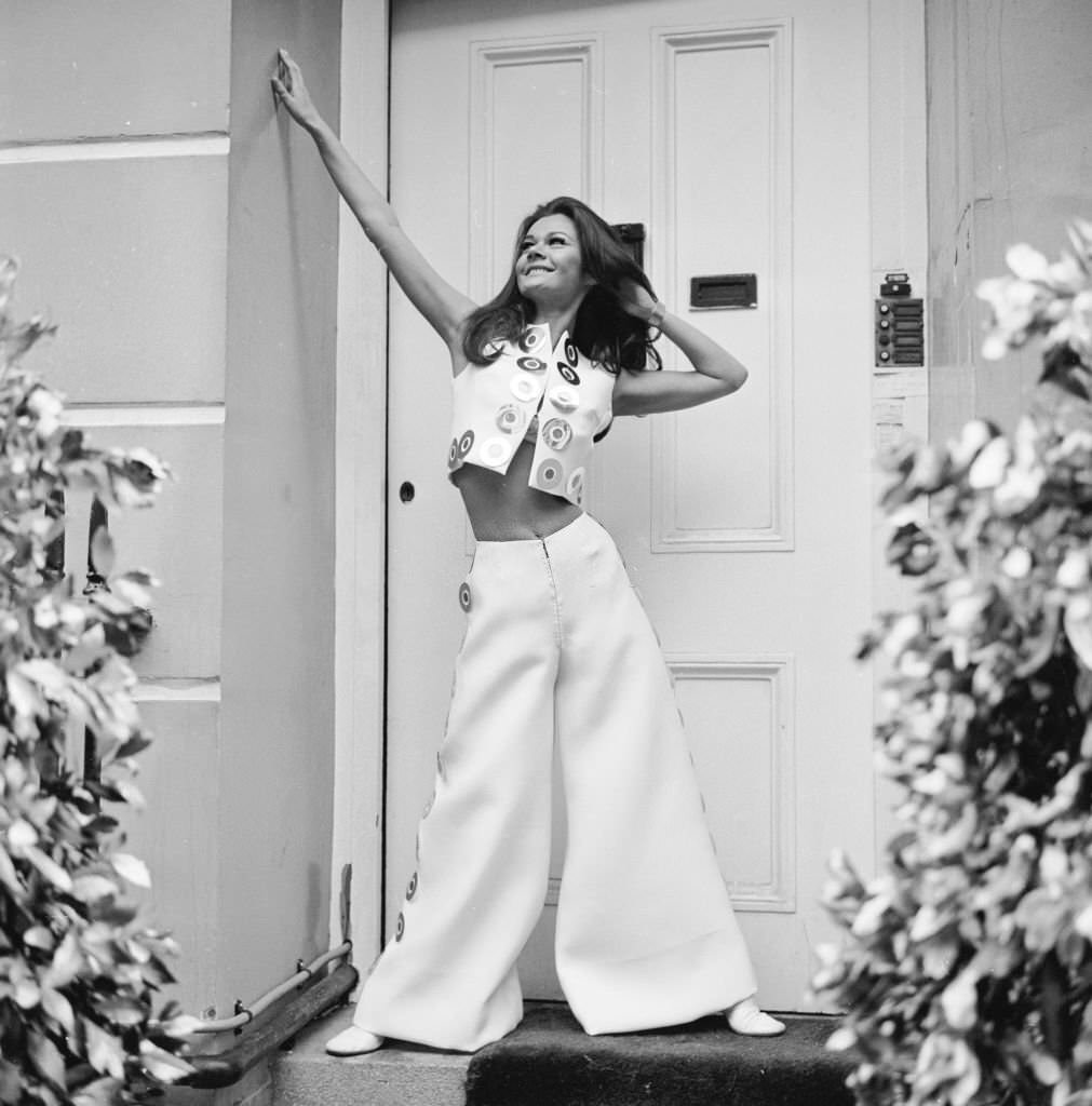 #21 British actress Imogen Hassall wearing white culottes and a mini bolero trimmed with silver and purple paillettes.