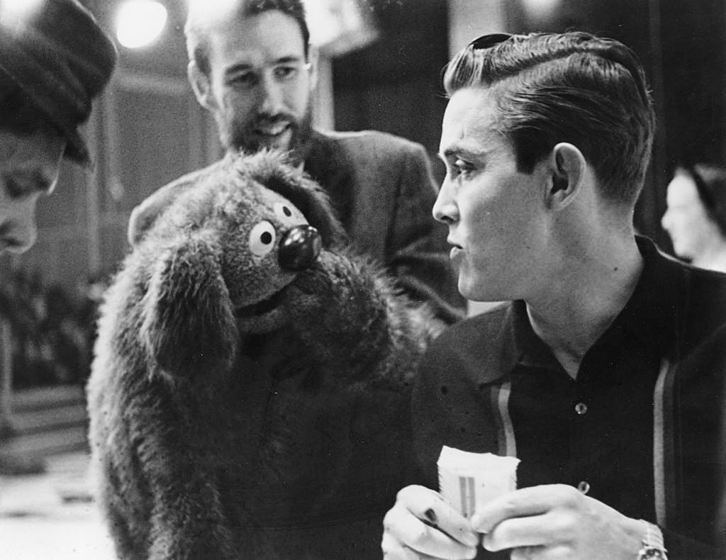 #11 Muppets creator Jim Henson, (beard, background), manipulates one of his creations as it engages in conversation with singer Jimmy Dean in 1963.