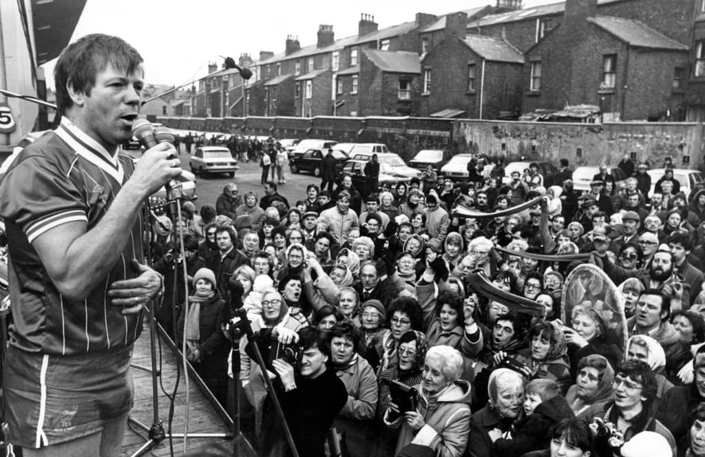 #129 Radio star Billy Butler entertains a crowd of 300 fans at Anfield with a version of Top anthem ‘You’ll Never Walk Alone’. Clad in a Liverpool FC strip, 1983