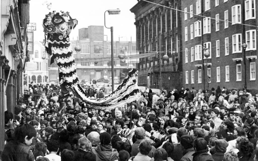 #166 A large crowd watches traditional celebrations for the Chinese New Year, Liverpool, Merseyside, 13th February 1983.