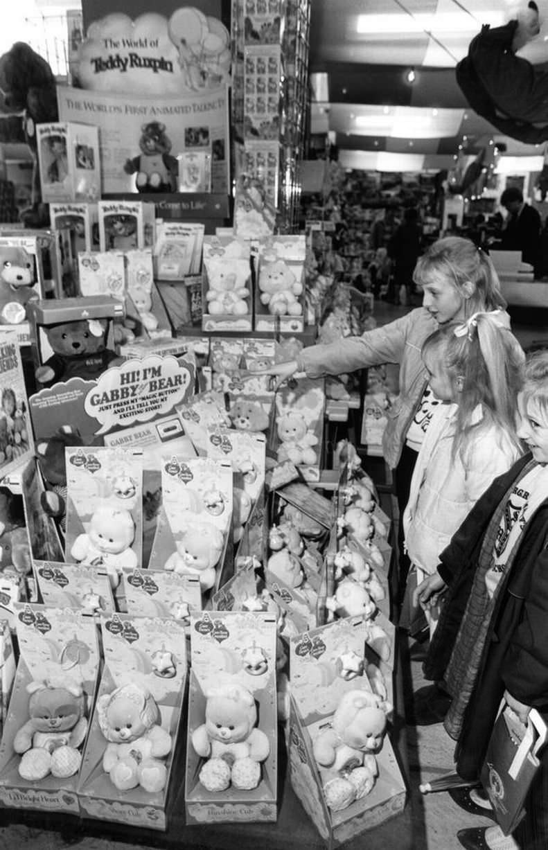 #18 Christmas Shopping Trip, 25th November 1986. Young girls examine Gabby Bear Dolls