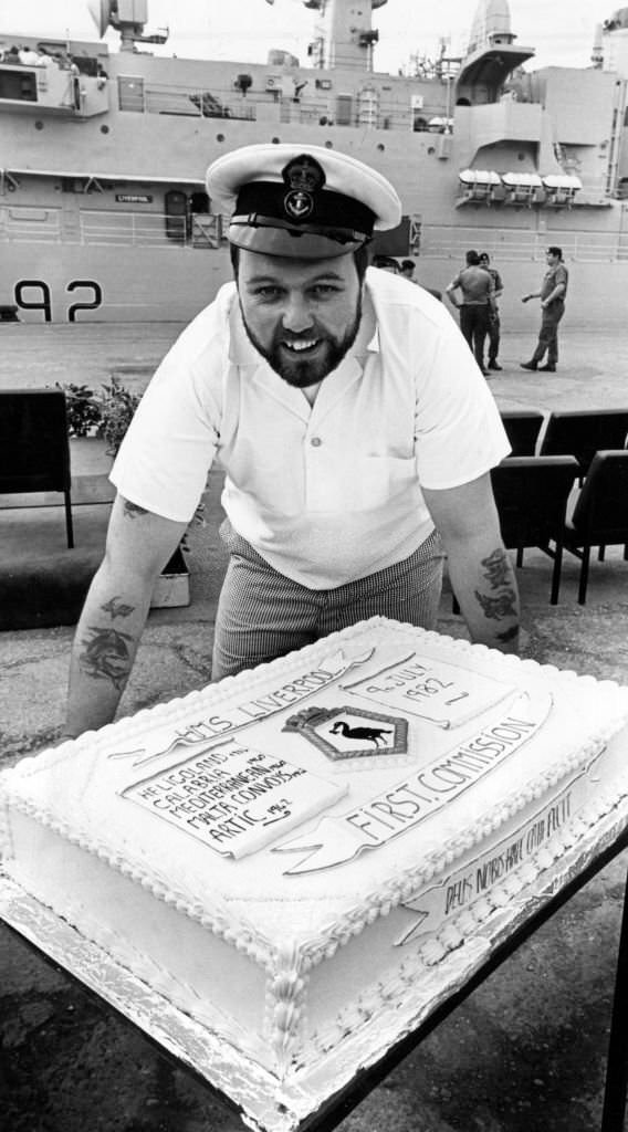 #86 Chef, Petty Officer Bill Colmer with the cake made to commemorate HMS Liverpool’s commissioning ceremony, 9th July 1982.