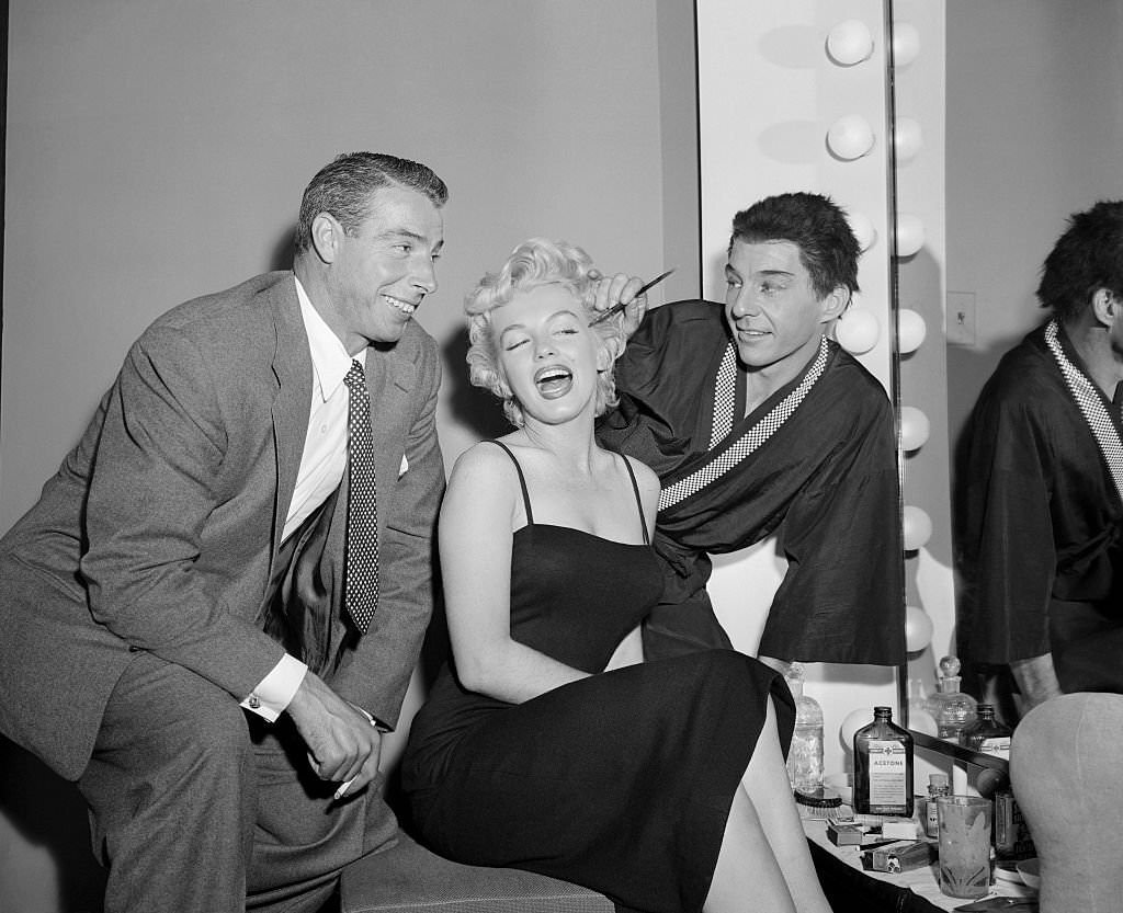 #12 David Wayne applies makeup to Marilyn Monroe while her husband Joe DiMaggio looks on.