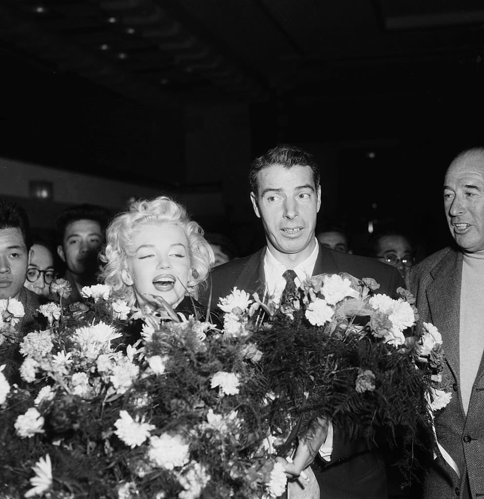 #19 Marilyn Monroe and Joe DiMaggio receive flower bouquets upon their arrival in Tokyo, where the famous couple will be spending their honeymoon.