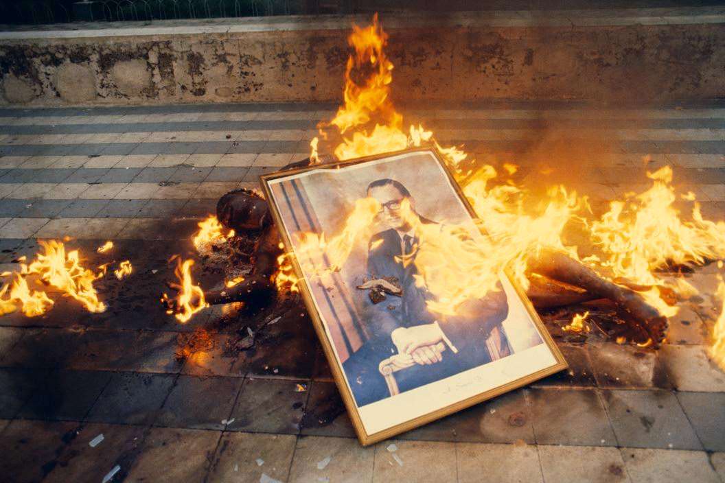 #71 Body of National Guardsman, killed during the taking of Jinotepe, being burned with the official state portrait of President Somoza, 1979