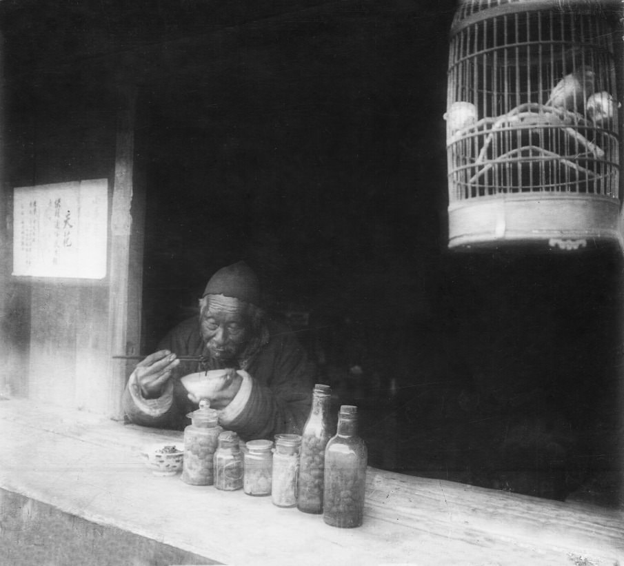 #15 Old man eating noodles in his shop, bird in a cage, Shanghai, 1923