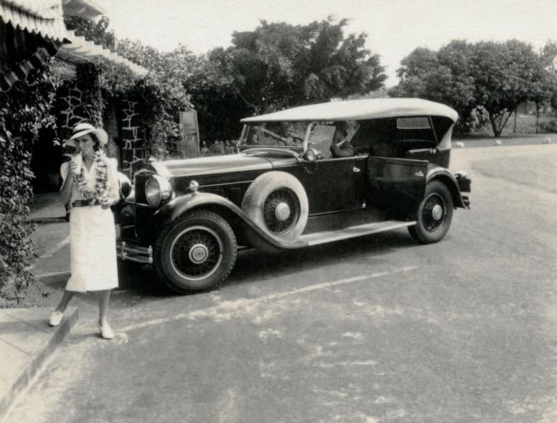 #10 A lady in a white dress with a garland of flowers around her neck sipping on a cocktail in an exotic location.