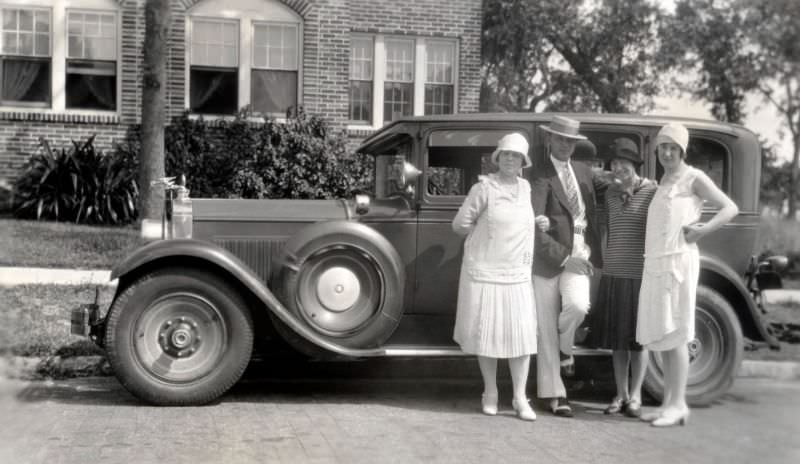 #4 Four stylish individuals posing with a 1928 Packard Sedan in front of a large brick-built house in summertime, 1928
