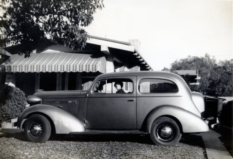 A stylish lady posing in the driver’s seat of a 1936 Pontiac Deluxe Six in the drive of a private home.