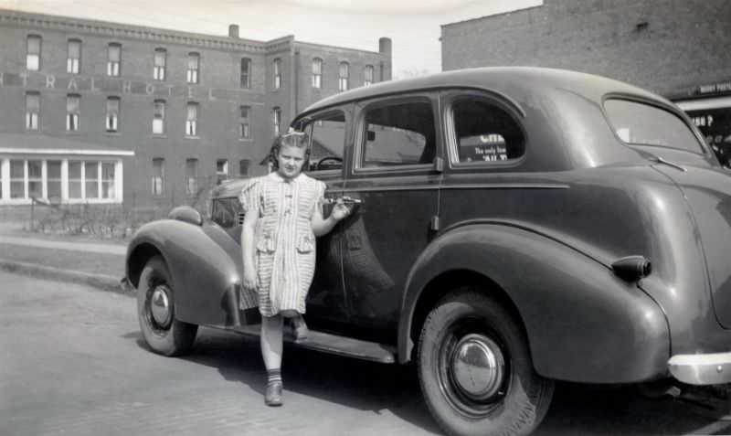#17 An adolescent girl in a striped dress posing on the running board of a 1939 Pontiac Sedan.