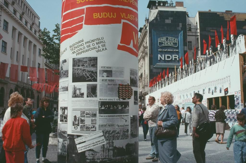 #36 People walking past a column showcasing political handouts, Prague, Czech Republic, June 1990.