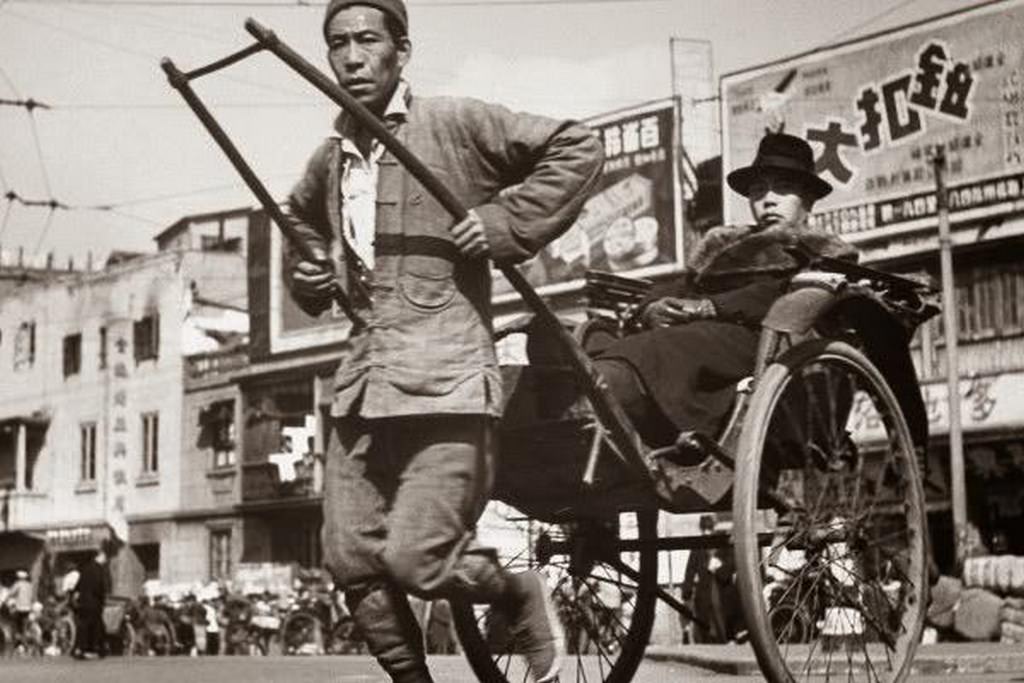 #101 A rickshaw puller, with a lot of advertisements visible on the commercial street.