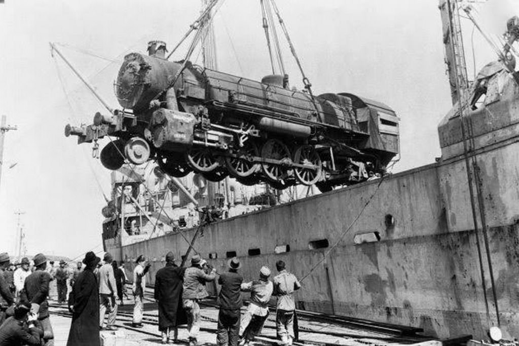 #95 Dockers unloading a train locomotive engine; this engine car was provided by the United Nations Relief and Rehabilitation Administration