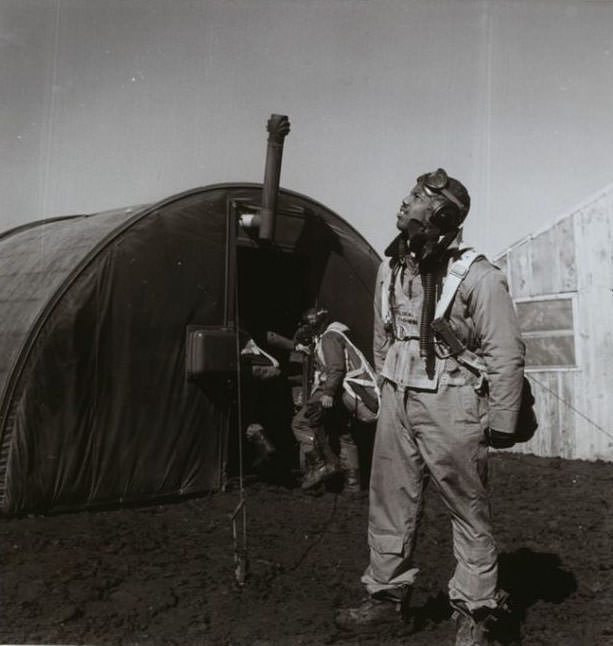 #7 Pilot Newman C. scanning the skies, with parachute room in background