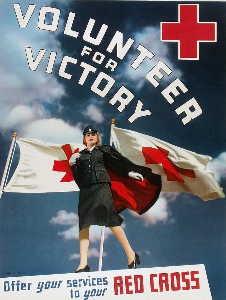 #139 A female Red Cross volunteer standing in front of two Red Cross flags.