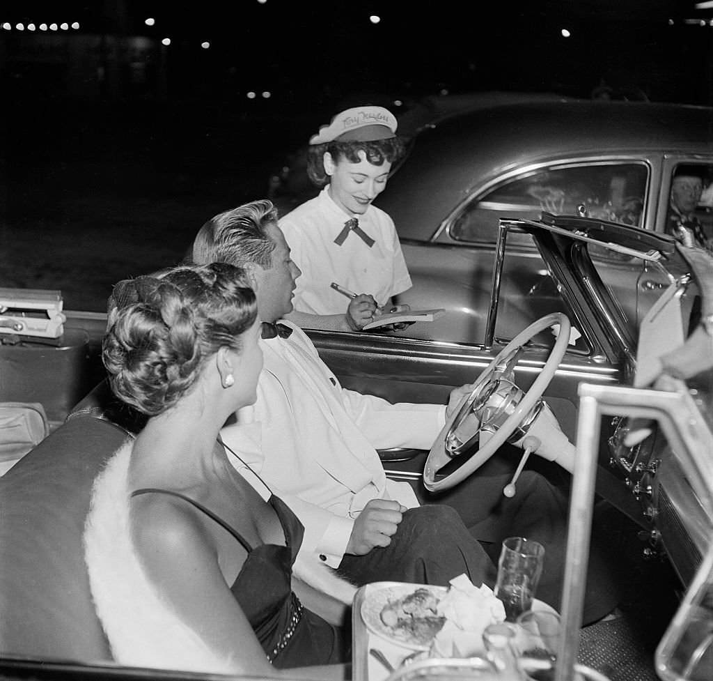#15 A young couple in a convertible order food at Tiny Naylor’s Drive-In Restaurant in Los Angeles, 1951