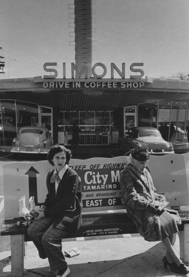 #17 Two women sit on a bench outside a Hollywood drive-in restaurant.