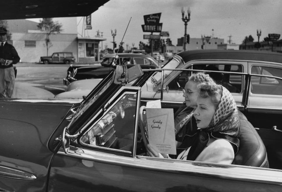 #18 A young motorist studies the menu at a Hollywood drive-in restaurant.