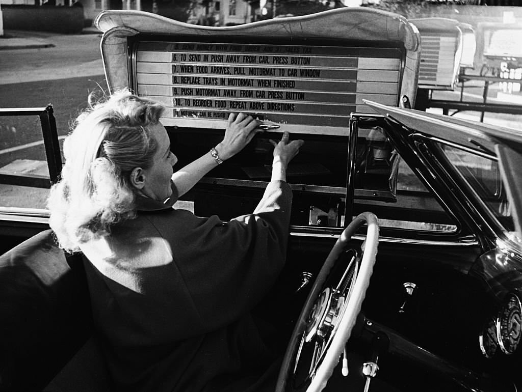 #20 A woman sitting in her convertible removes a lunch tray from the Auto-Motor mart.