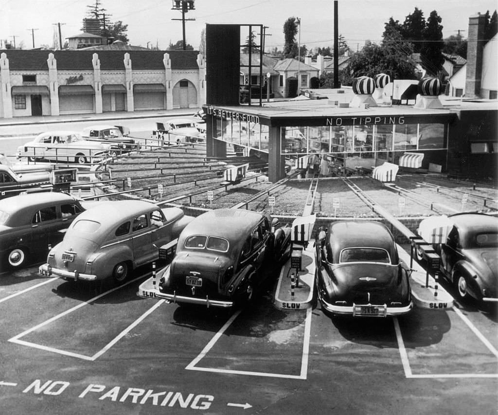 #21 Cars parked at an automated drive-in diner, where individual conveyor belts transport food directly to the driver, Califonia, 1950.