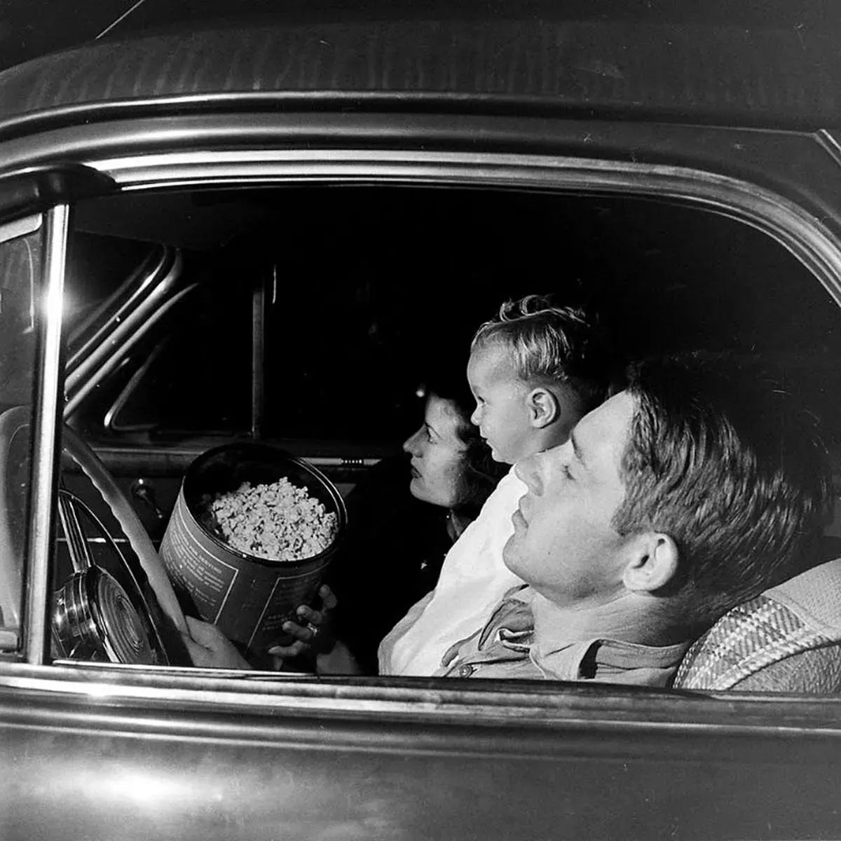 #43 A late night at the drive-in, a couple and their young son watch a film while they sit in their ’41 Buick coupe, with almost an equally large canister of popcorn.