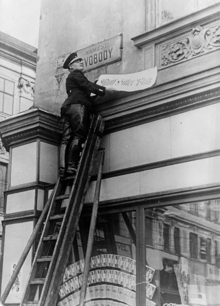 #114 A jack booted official changing the name of a street in Brunn, Czechoslovakia, to ‘Adolf Hitler Platz’ after the German invasion.