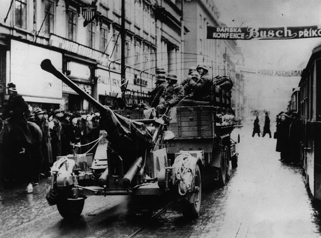 #49 German troops entering Prague by lorry, towing anti-aircraft guns.