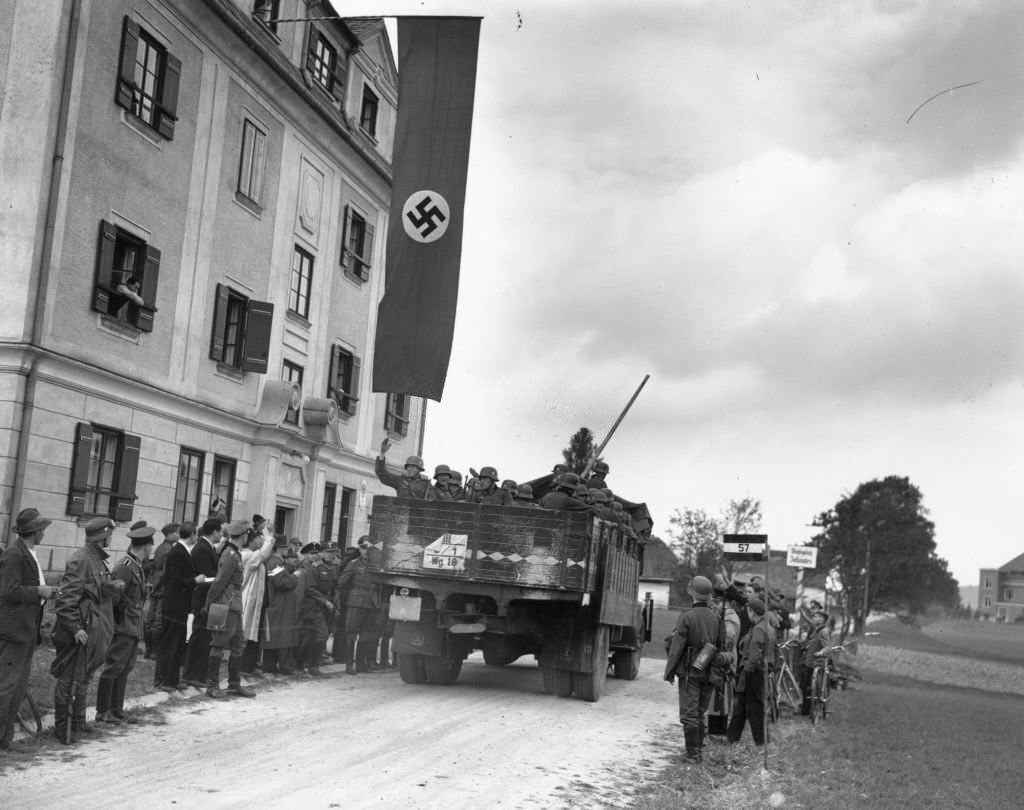 #73 German armoured vehicles pass through a customs barrier between Germany and Czechoslovakia.