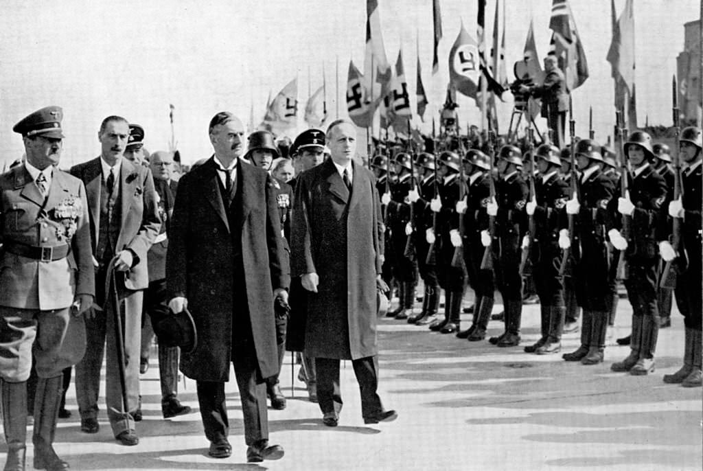 #86 British Prime Minister Neville Chamberlain passes a Germn honour guard on his arrival at Oberwiesenfeld airport before a meeting with Adolf Hitler over the latter’s threats to invade Czechoslovakia, 29th September 1938.