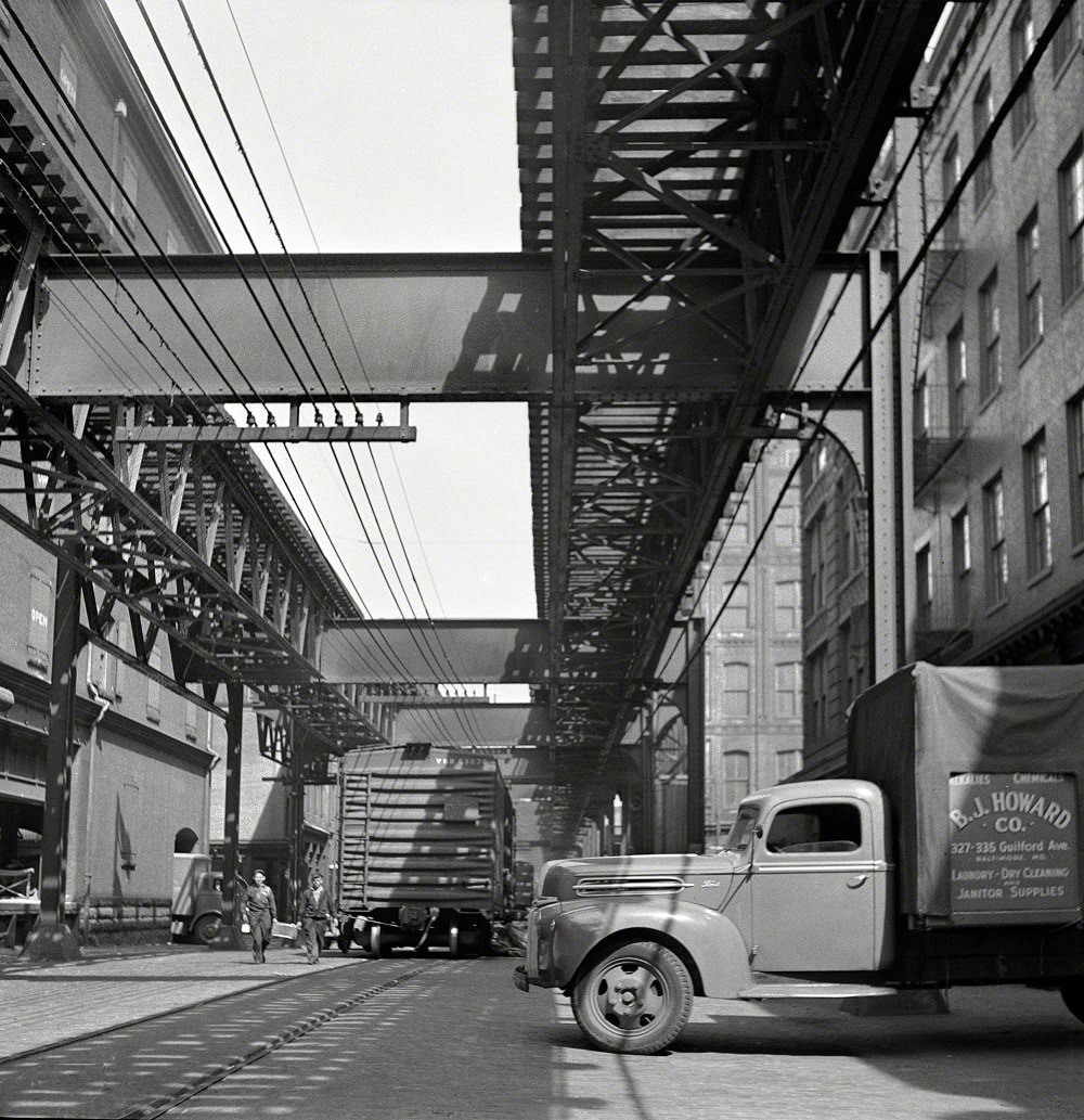 #59 Trucks and trains unloading goods underneath elevated trolley, Baltimore, Maryland, April 1943