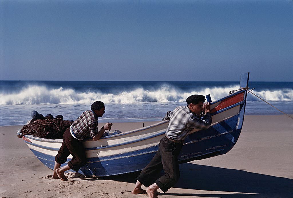#25 Fishermen pulling their boat up the beach at Nazare, Portugal, 1952.