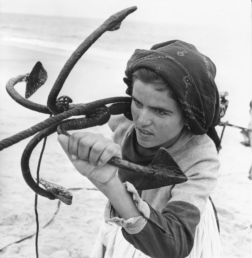 #10 A woman helps to pull in the fishing boats at Peniche, Portugal.