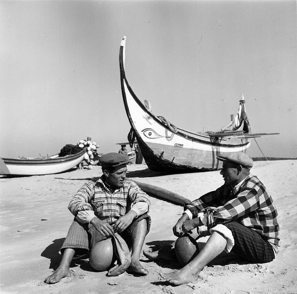 #28 Portuguese fishermen relax near their traditional fishing boats on a beach near Lisbon.