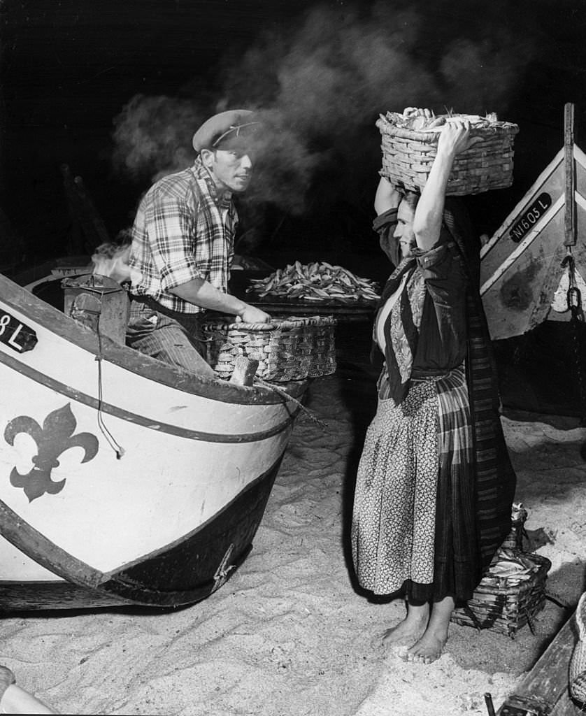 #30 A fisherman and woman sell fresh fish from their boat in Nazare, a Portuguese fishing village.