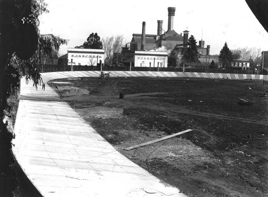 #64 Agricultural Park bicycle track, in disrepair, with the San Jose & Santa Clara Railroad Company buildings and Fredericksburg Brewery in the background, 1951