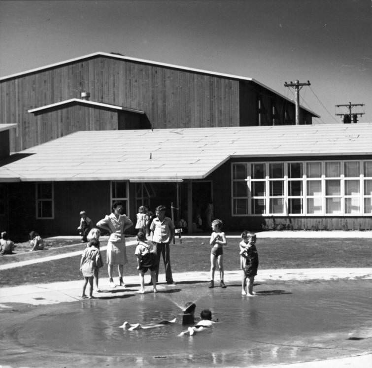 #30 Children play in a wading pool outside a building. V.H.A, 1950s