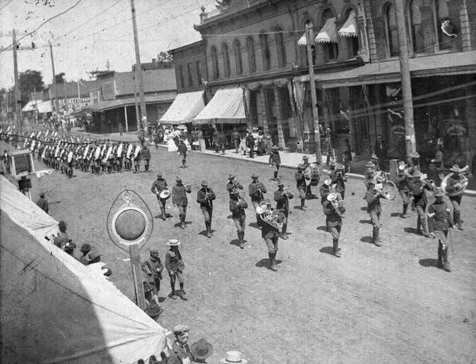 #65 Military marching band parading down a street in Vancouver, Washington in 1906.