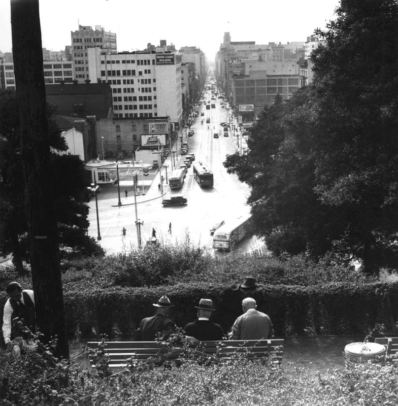 #139 Three men relaxed on a bench overlooking South Hill Street in Los Angeles.