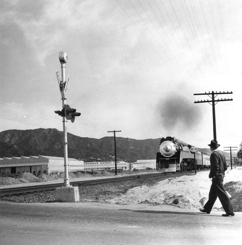 #140 A man on an unidentified street in Burbank. In the distance is a Lockheed plant.