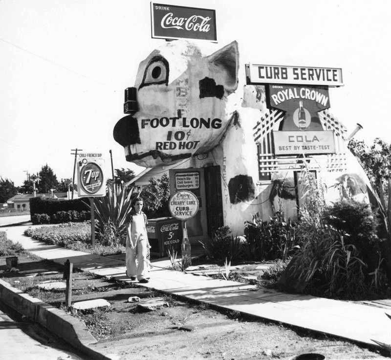#81 A young man walked by a hot dog stand on Washington Boulevard.