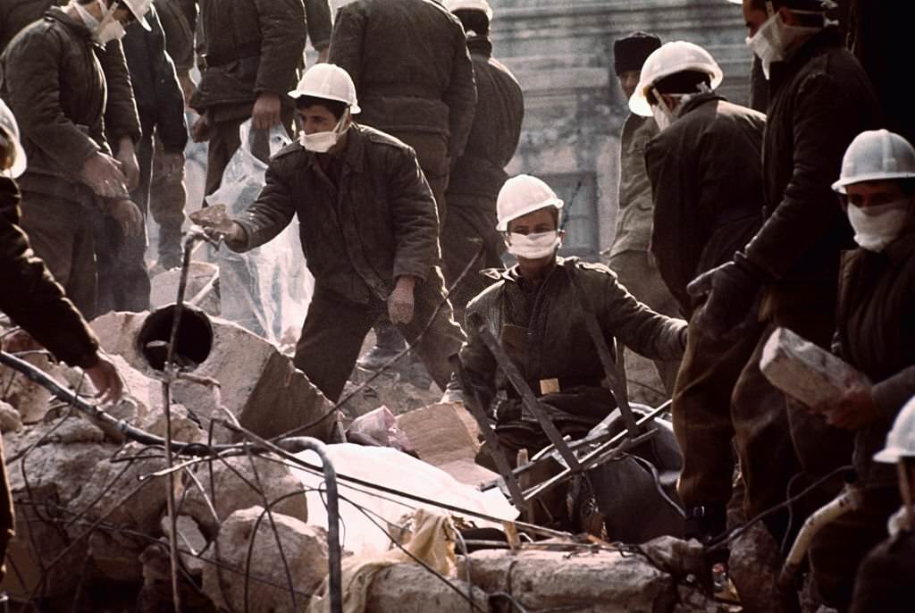 #97 Rescue workers are shown here in Bucharest, Romania wearing face mask protection trying to clean up after the destructive earthquake.